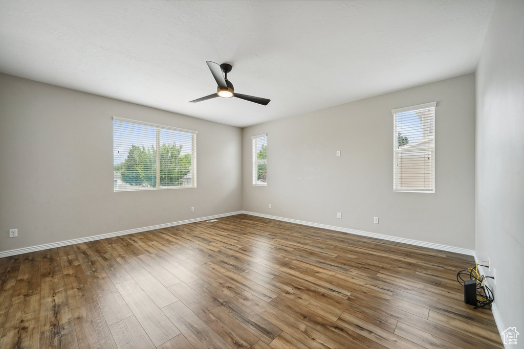 Spare room with ceiling fan, wood finished floors, and baseboards