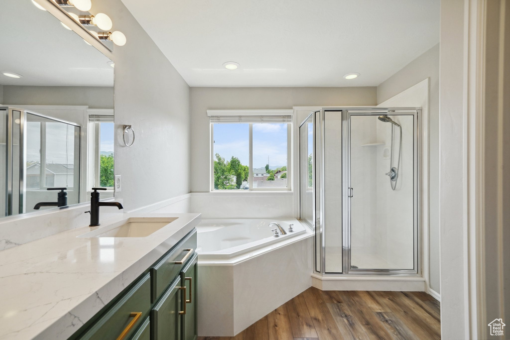 Bathroom featuring wood finished floors, a stall shower, a garden tub, vanity, and recessed lighting