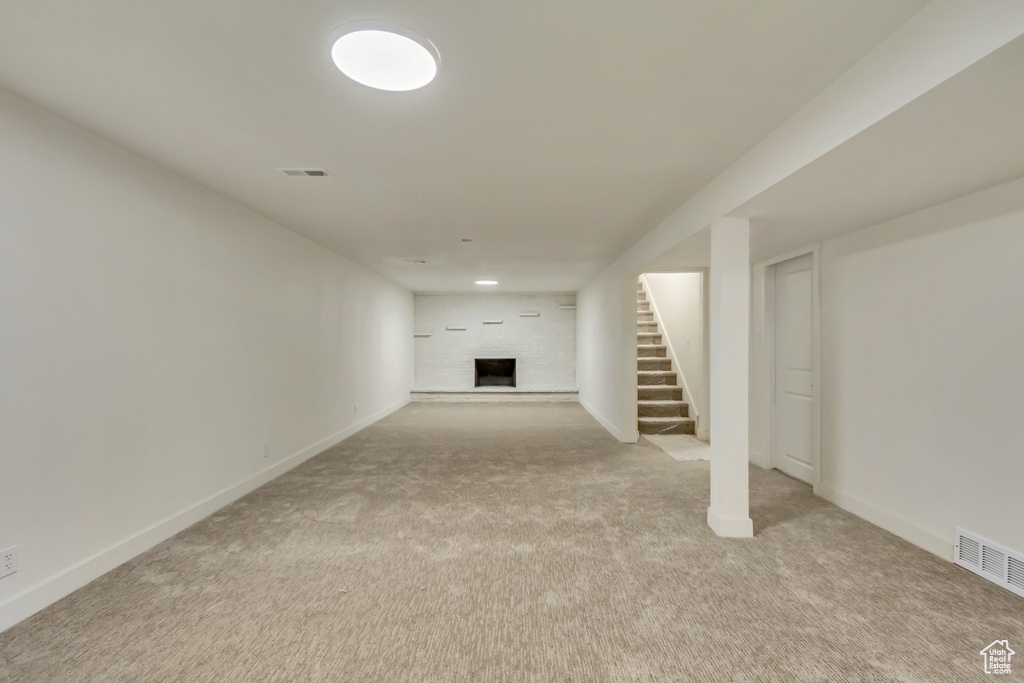 Finished below grade area with stairs, carpet, a fireplace with raised hearth, and baseboards
