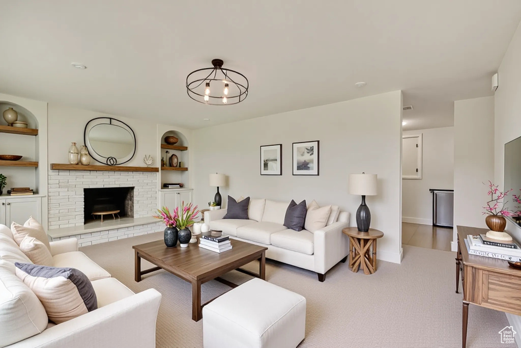 Living area with carpet flooring, a fireplace, built in features, baseboards, and a chandelier
