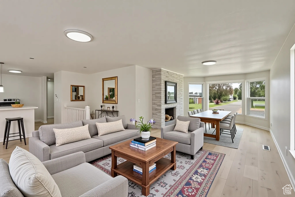Living area with light wood finished floors, a stone fireplace, and baseboards