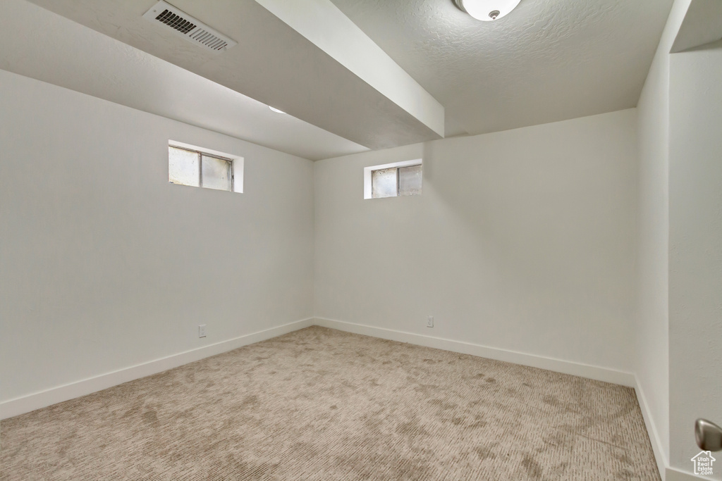 Below grade area featuring carpet floors, baseboards, and a textured ceiling