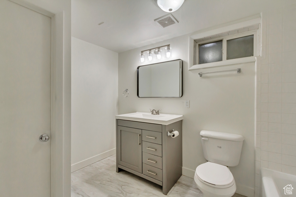Full bath featuring baseboards, toilet, vanity, a tub, and a shower