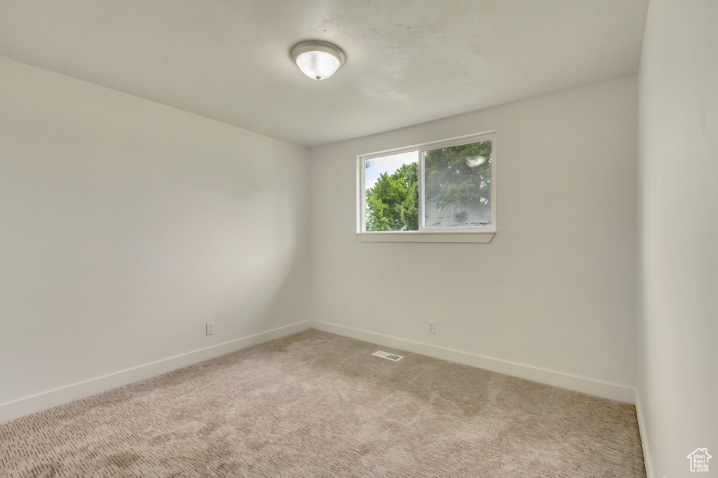 Spare room featuring baseboards and light carpet