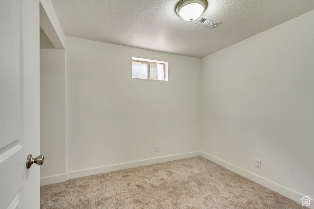 Carpeted spare room featuring a textured ceiling and baseboards