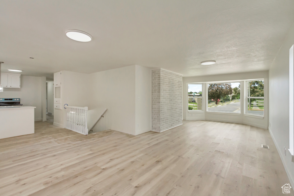 Unfurnished living room with light wood finished floors and baseboards
