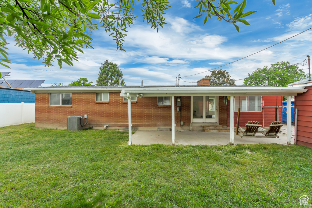 Back of property featuring central AC unit, a chimney, brick siding, and a patio