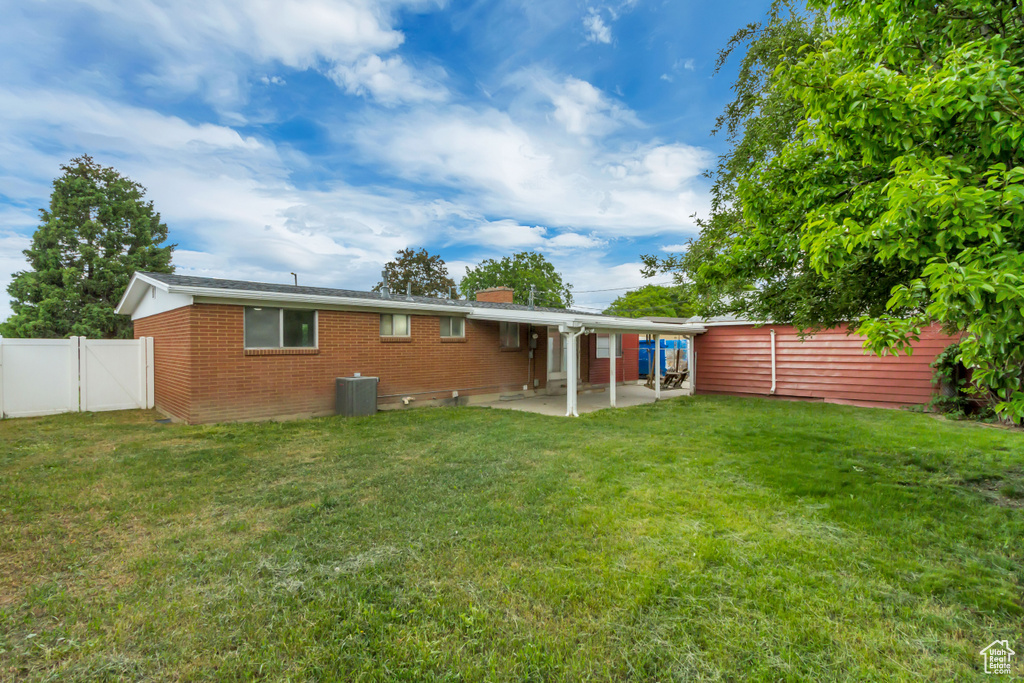 Rear view of property with a patio, brick siding, a chimney, and central AC