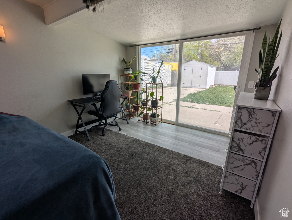 Bedroom featuring access to exterior, a wall of windows, a textured ceiling, wood finished floors, and baseboards