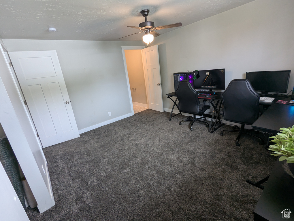 Carpeted office space with ceiling fan and baseboards
