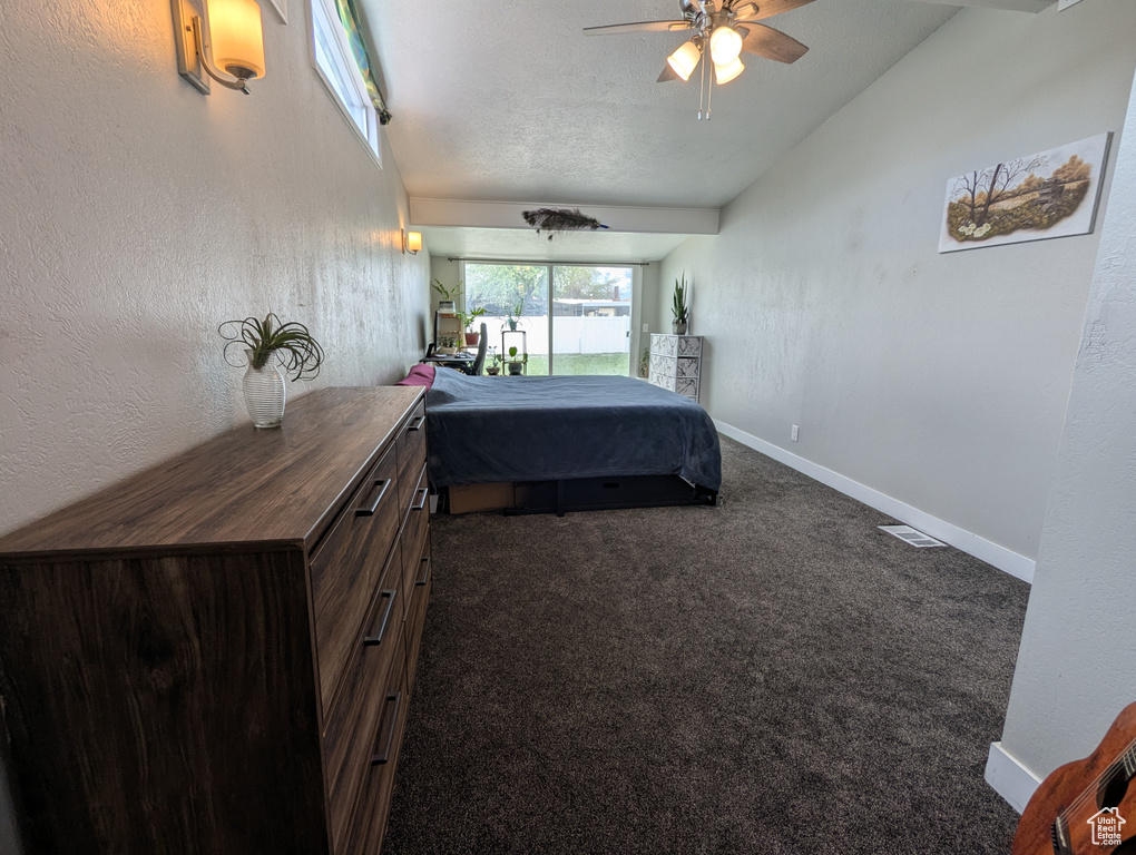 Carpeted bedroom with vaulted ceiling, baseboards, and a textured ceiling