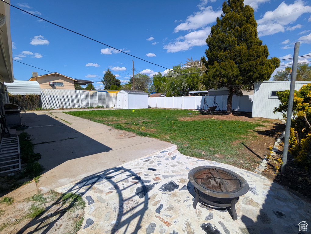 View of yard featuring a storage shed, an outdoor fire pit, a patio area, and an outbuilding