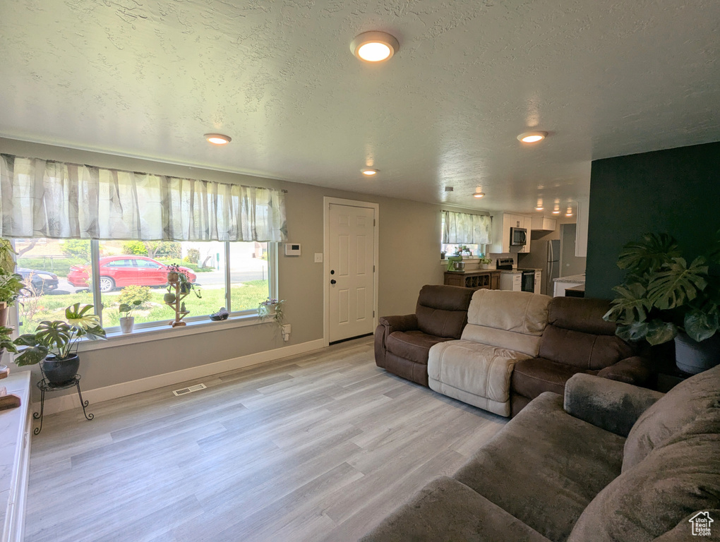 Living room featuring light wood finished floors, baseboards, and recessed lighting