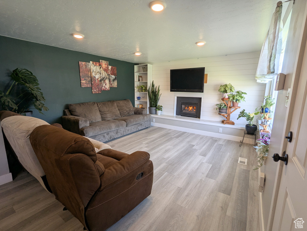 Living area featuring a glass covered fireplace, wood finished floors, recessed lighting, and baseboards