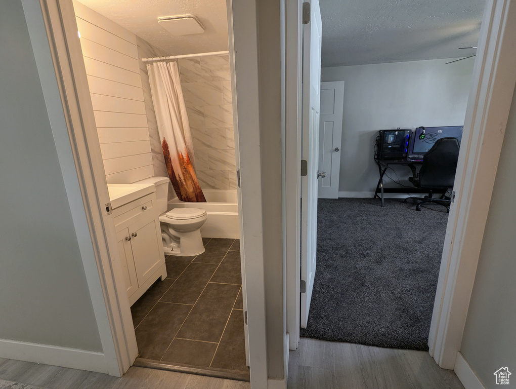 Bathroom with vanity, shower / bath combo, toilet, baseboards, and a textured ceiling