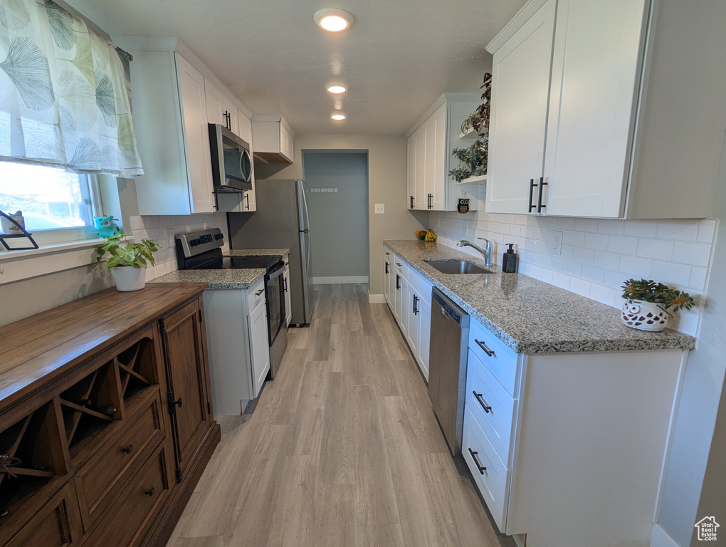 Kitchen featuring appliances with stainless steel finishes, a sink, open shelves, white cabinets, and recessed lighting