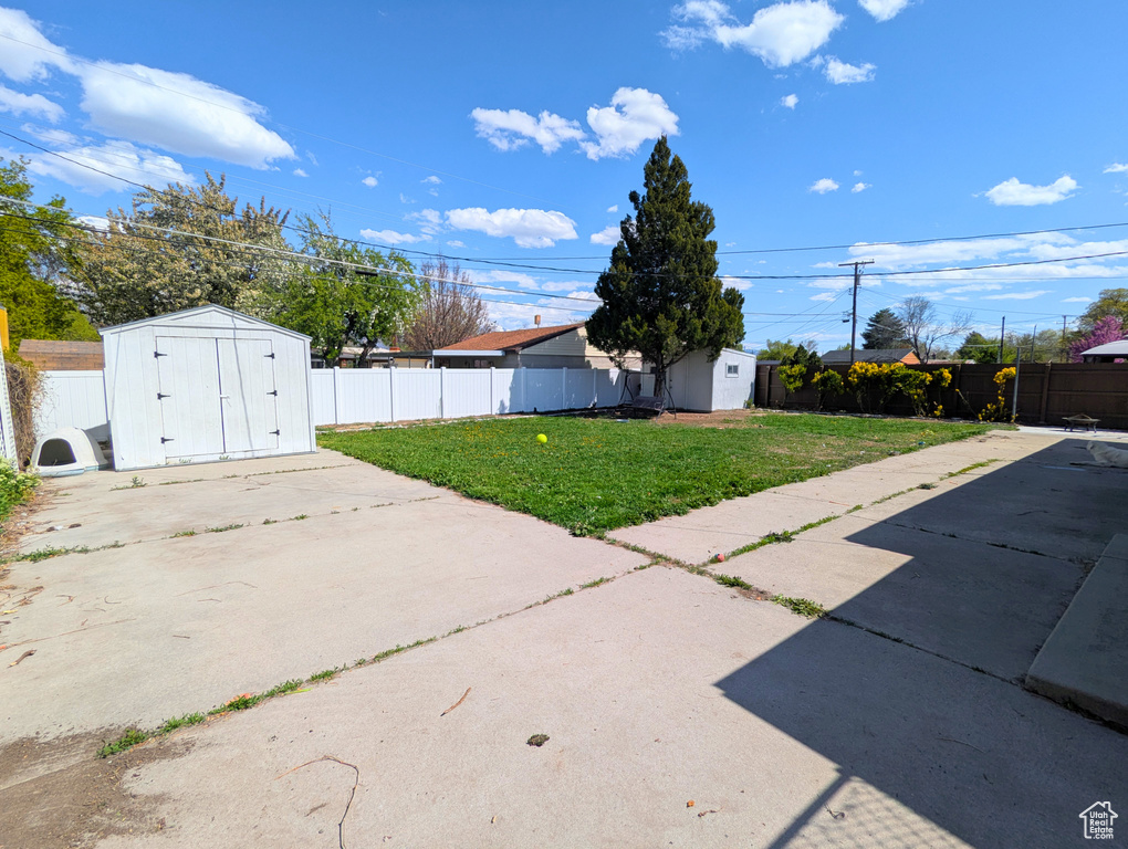 View of yard featuring a storage shed, a patio area, and an outbuilding