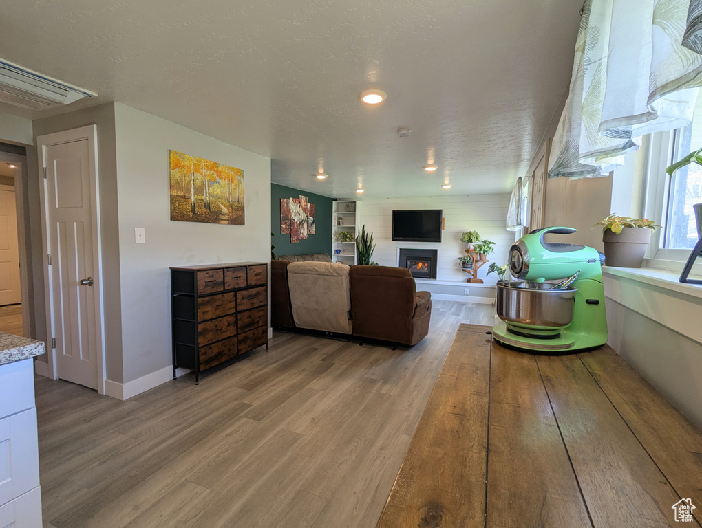 Living area featuring light wood-style floors, a warm lit fireplace, baseboards, and recessed lighting