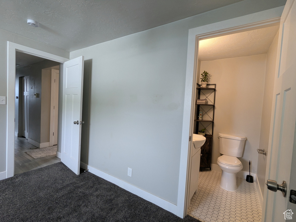 Bathroom with toilet, baseboards, and a textured ceiling