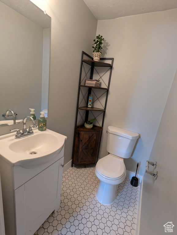 Half bathroom with toilet, vanity, and baseboards