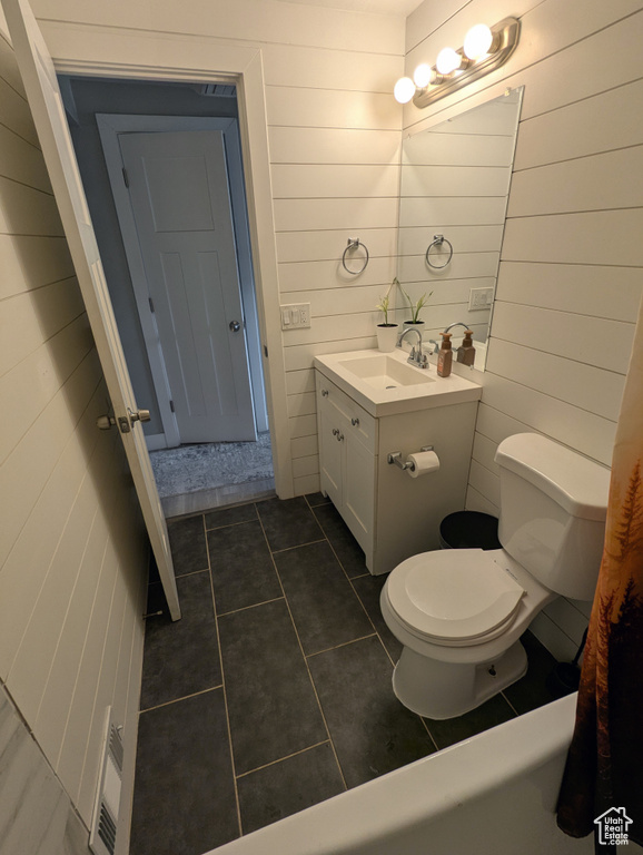 Bathroom featuring toilet, tile patterned flooring, vanity, and wood walls