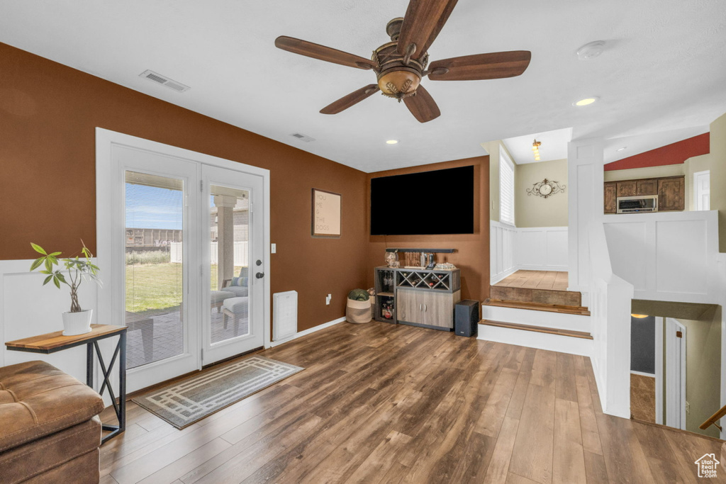 Living room featuring wood finished floors, ceiling fan, a wainscoted wall, and recessed lighting
