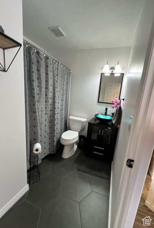 Bathroom with toilet, vanity, and curtained shower