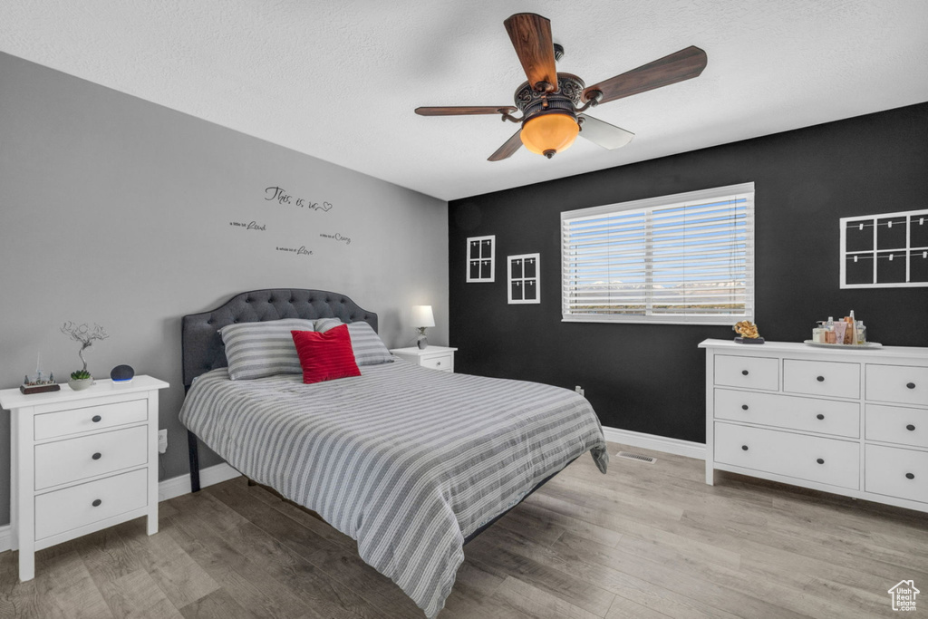 Bedroom with light wood finished floors, baseboards, and a ceiling fan