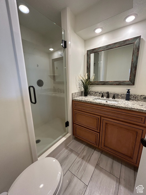 Full bath featuring a stall shower, vanity, and toilet