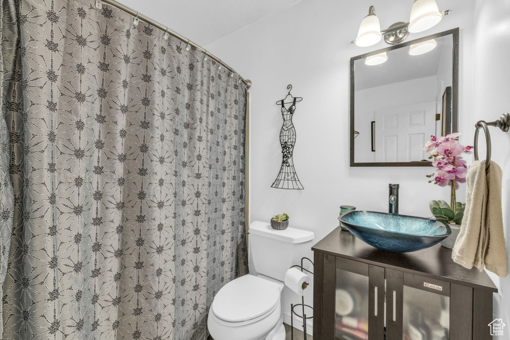 Full bath with toilet, vanity, and a shower with shower curtain
