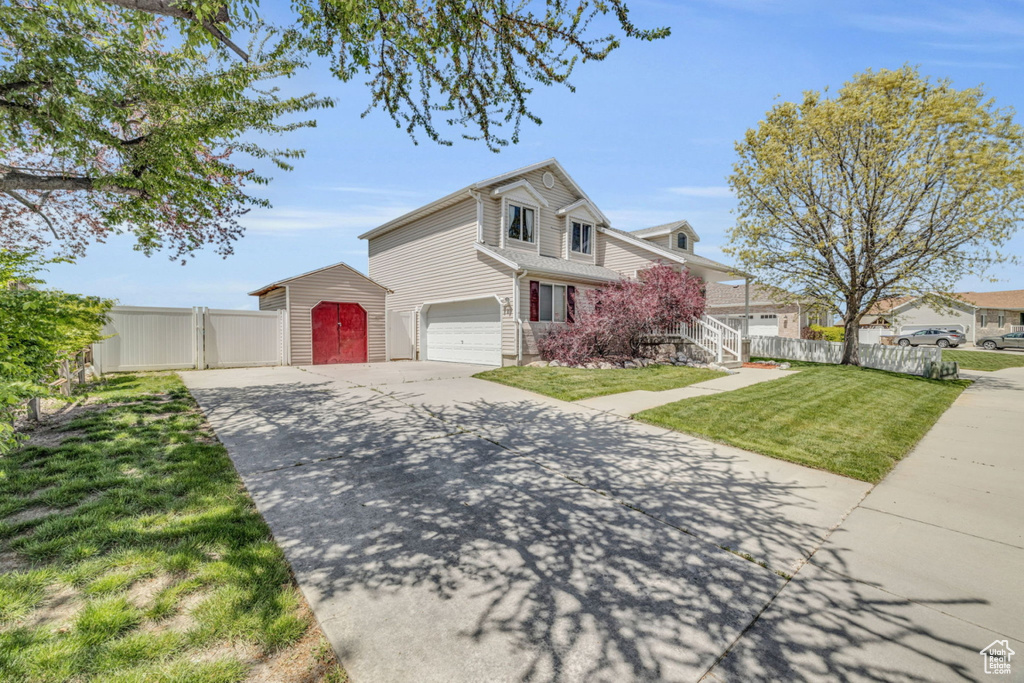 Traditional-style home with driveway, a garage, a shed, and an outbuilding