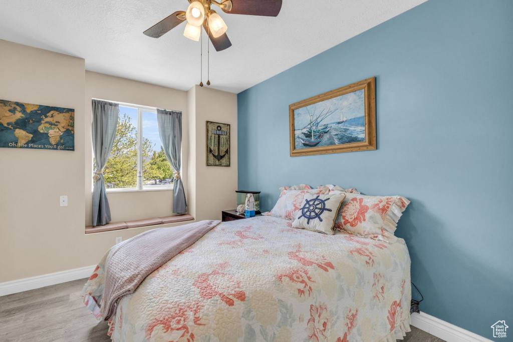 Bedroom with baseboards, wood finished floors, and ceiling fan