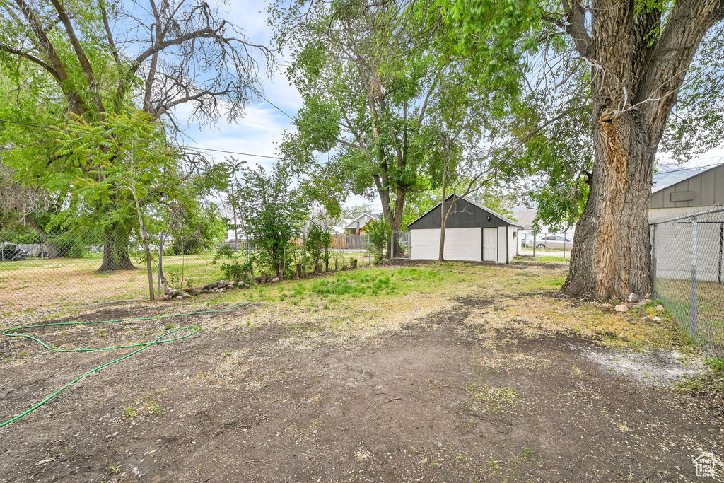 View of yard with fence, a detached garage, dirt driveway, and an outbuilding