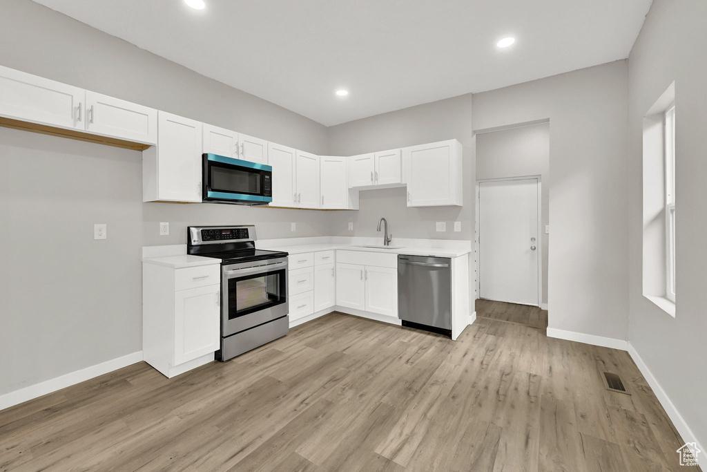 Kitchen featuring appliances with stainless steel finishes, a sink, light countertops, baseboards, and recessed lighting
