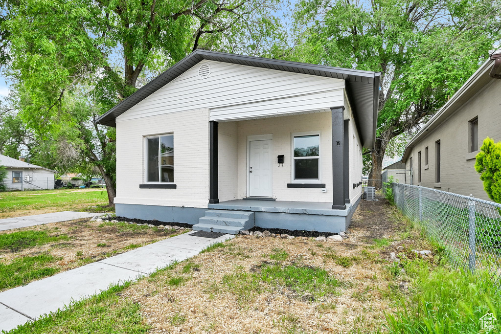 Shotgun-style home featuring fence, brick siding, and a porch