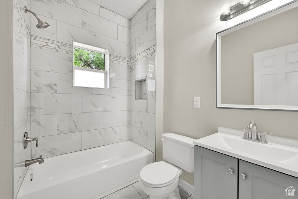 Full bathroom featuring toilet, vanity, bathtub / shower combination, and baseboards