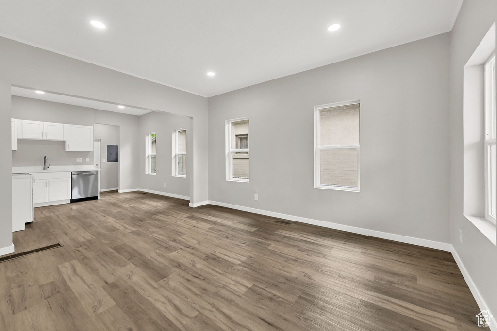 Unfurnished living room featuring a sink, wood finished floors, baseboards, and recessed lighting