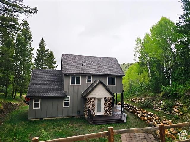 Back of house featuring board and batten siding and roof with shingles