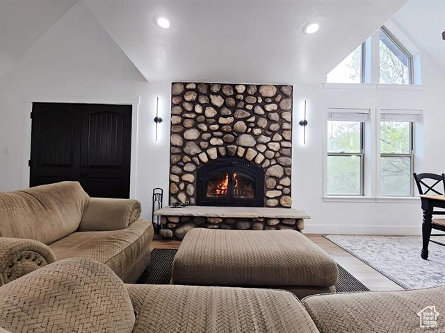 Living room featuring lofted ceiling, a fireplace, baseboards, wood finished floors, and recessed lighting