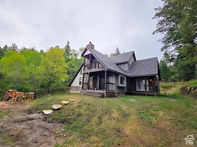 Back of house featuring a chimney and a lawn