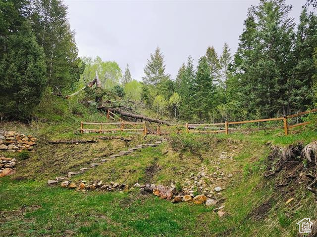 View of yard with fence and a view of trees
