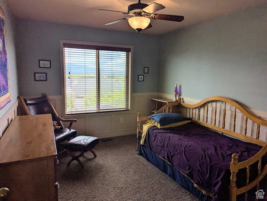 Bedroom with carpet floors, a wainscoted wall, and ceiling fan