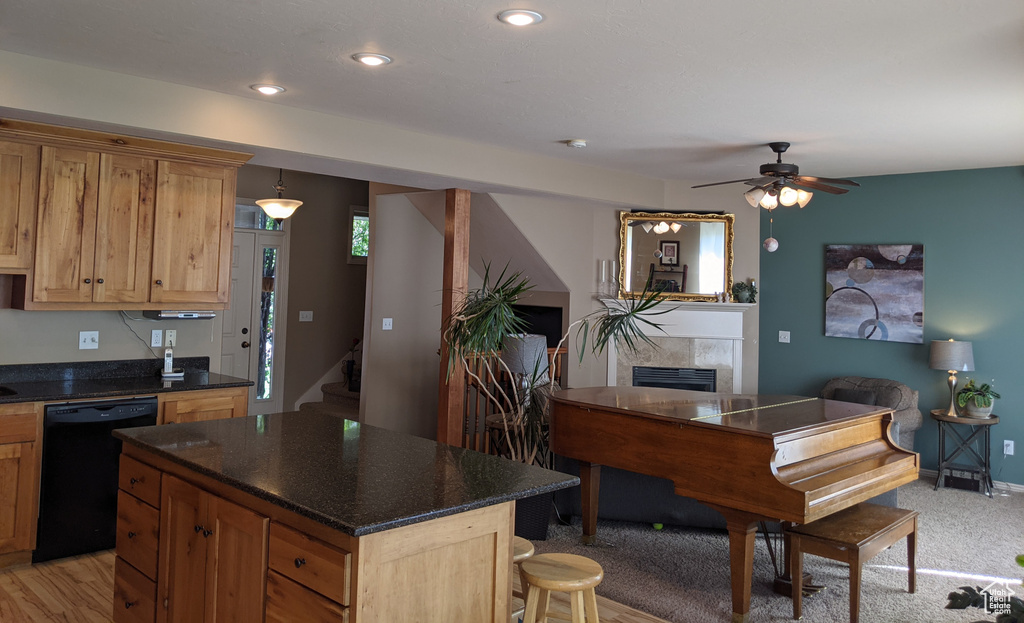 Kitchen featuring black dishwasher, a tiled fireplace, ceiling fan, recessed lighting, and a kitchen island