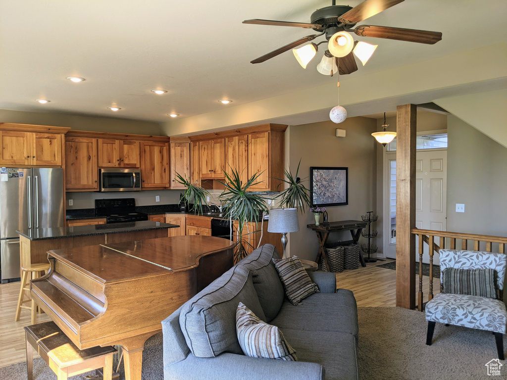Living area featuring light wood-style floors, ceiling fan, and recessed lighting