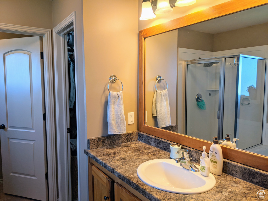 Full bath featuring a stall shower, vanity, and a spacious closet