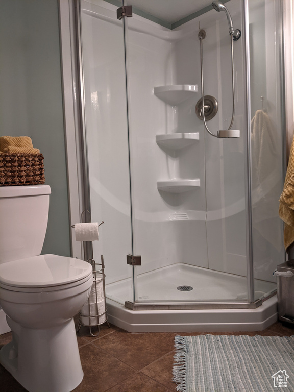 Full bathroom featuring a stall shower, toilet, and tile patterned flooring