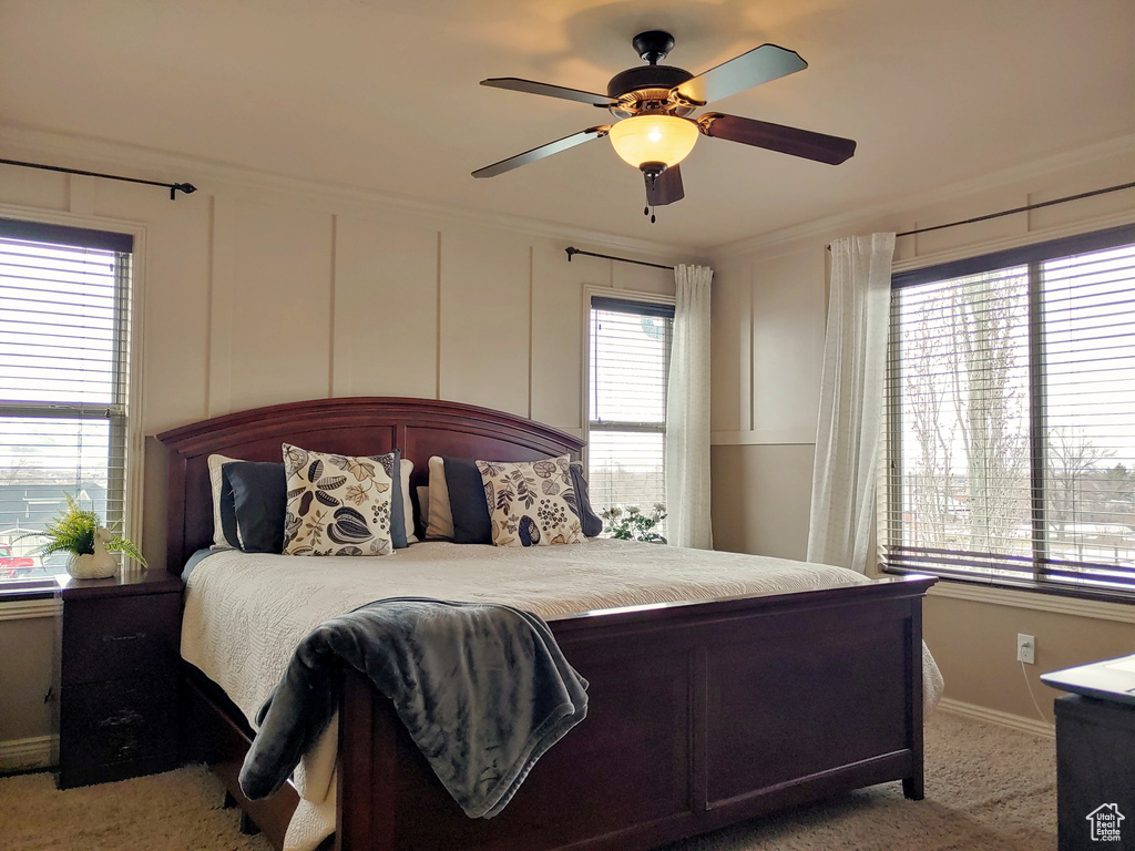 Bedroom with light colored carpet, baseboards, ornamental molding, and ceiling fan
