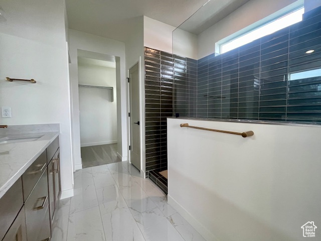 Full bathroom featuring walk in shower, marble finish flooring, vanity, baseboards, and a walk in closet