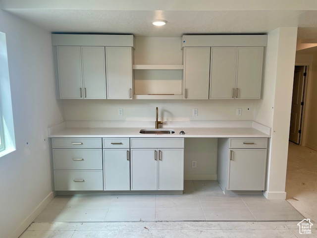 Kitchen featuring a sink, gray cabinetry, baseboards, and light countertops