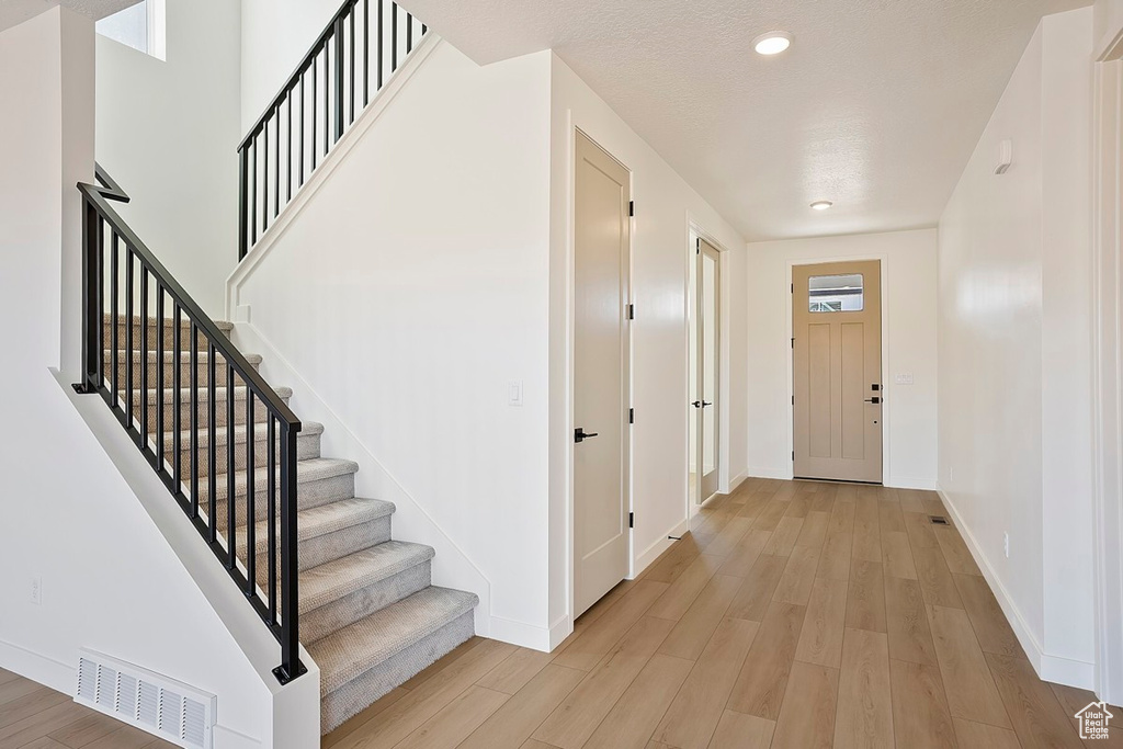 Foyer entrance with light wood-style flooring, stairs, baseboards, and recessed lighting